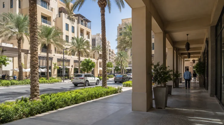 A contemporary Dubai-style neighbourhood with shaded walkways, warm masonry and palms.