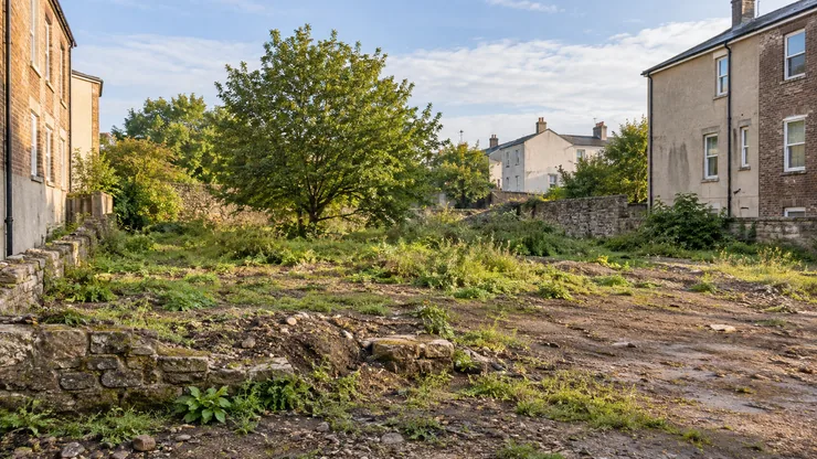 An undeveloped parcel of land surrounded by established urban buildings.